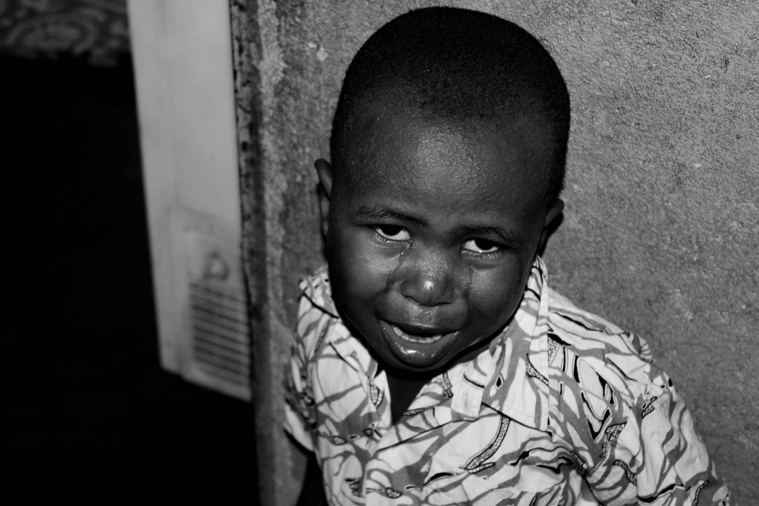 Crying child with a tear on the cheek against a wall, conveying trauma and need for counselling and therapy support in Liverpool