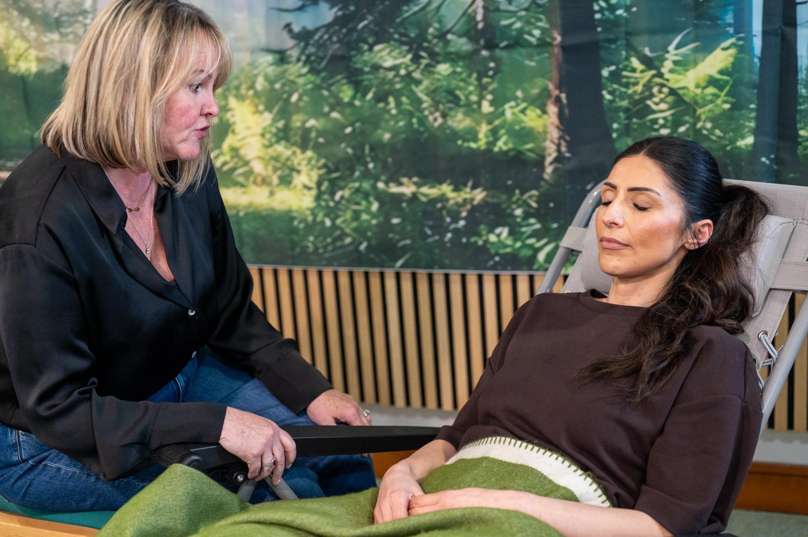 Therapist talking to a reclining client with eyes closed, green blanket, forest mural backdrop, hypnotherapy training in Liverpool.