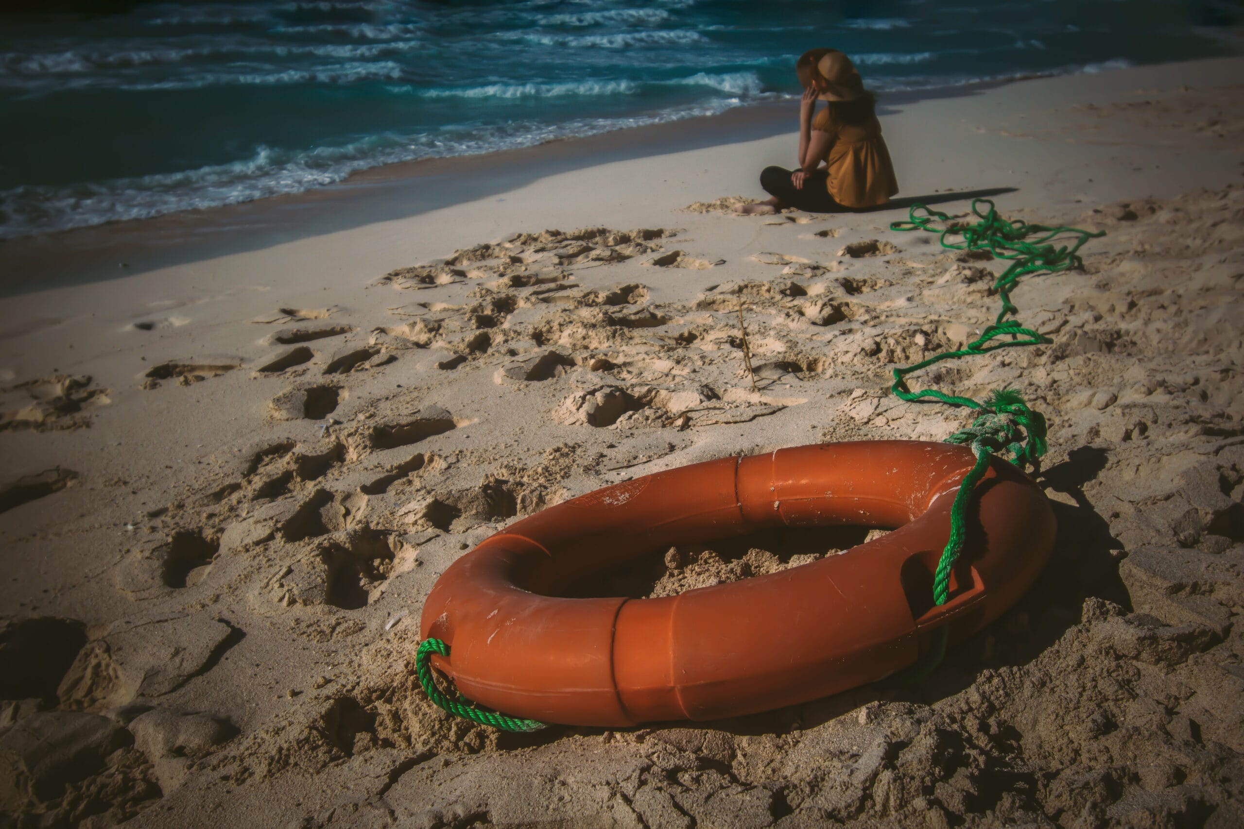 Self-Hypnosis: Techniques, Benefits, and Clinical Applications 11 Lifebuoy on sandy beach, woman sitting by sea — evokes mindfulness and relaxation for counselling training in Liverpool