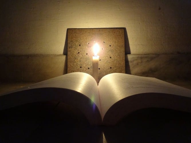 Metaphor in Therapeutic Practice: Storytelling as a Tool for Change 8 Open book lit by candle, symbolising reflective practice and evidence-based counselling training in Liverpool