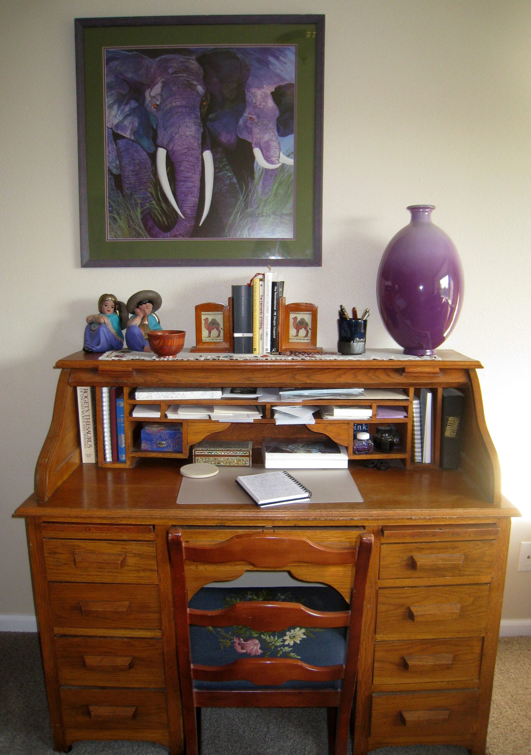 Setting Up a Hypnotherapy Practice: From Qualification to Confident Practitioner 1 Wooden writing desk with notebook, books and purple vase, elephant print above, study space for counselling training in Liverpool